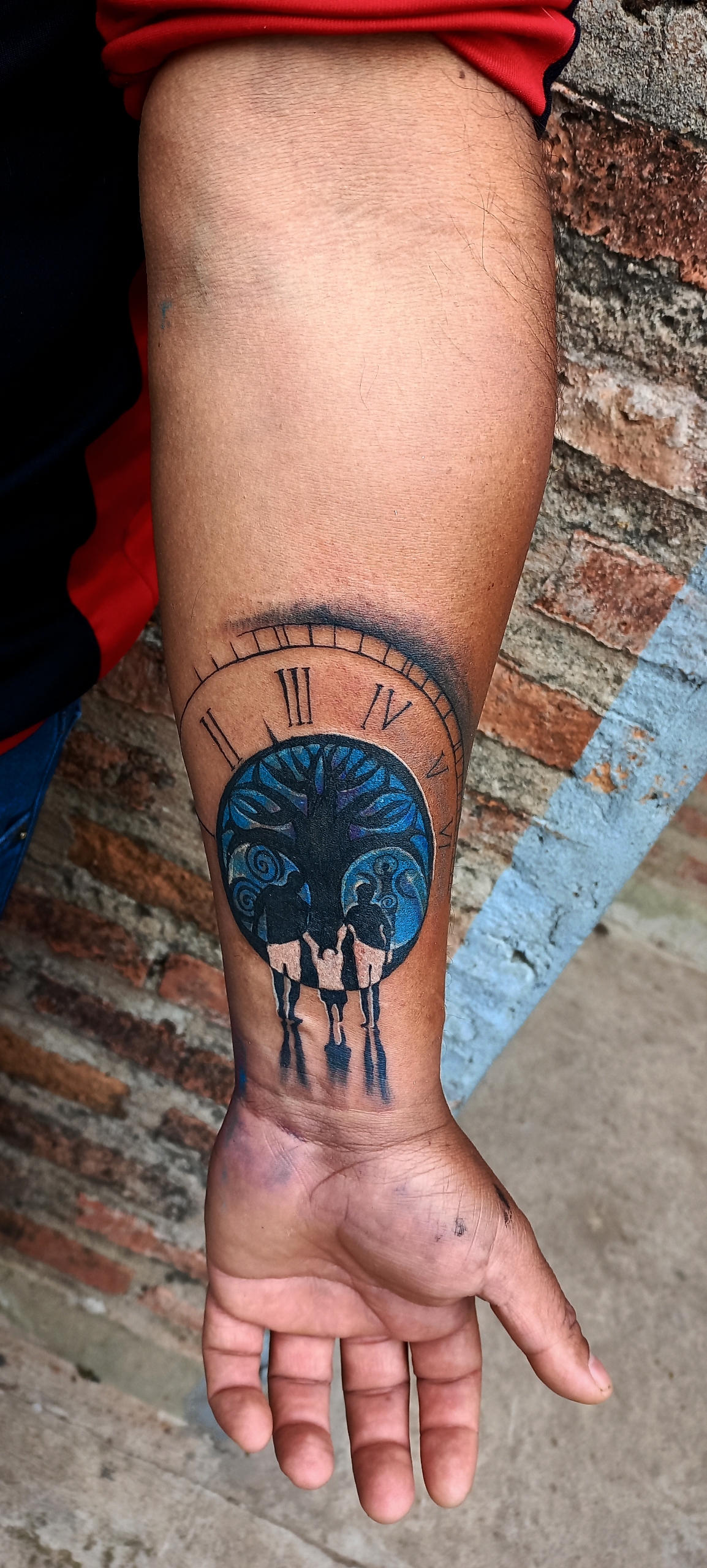 Reloj y árbol de la vida con figuras en antebrazo