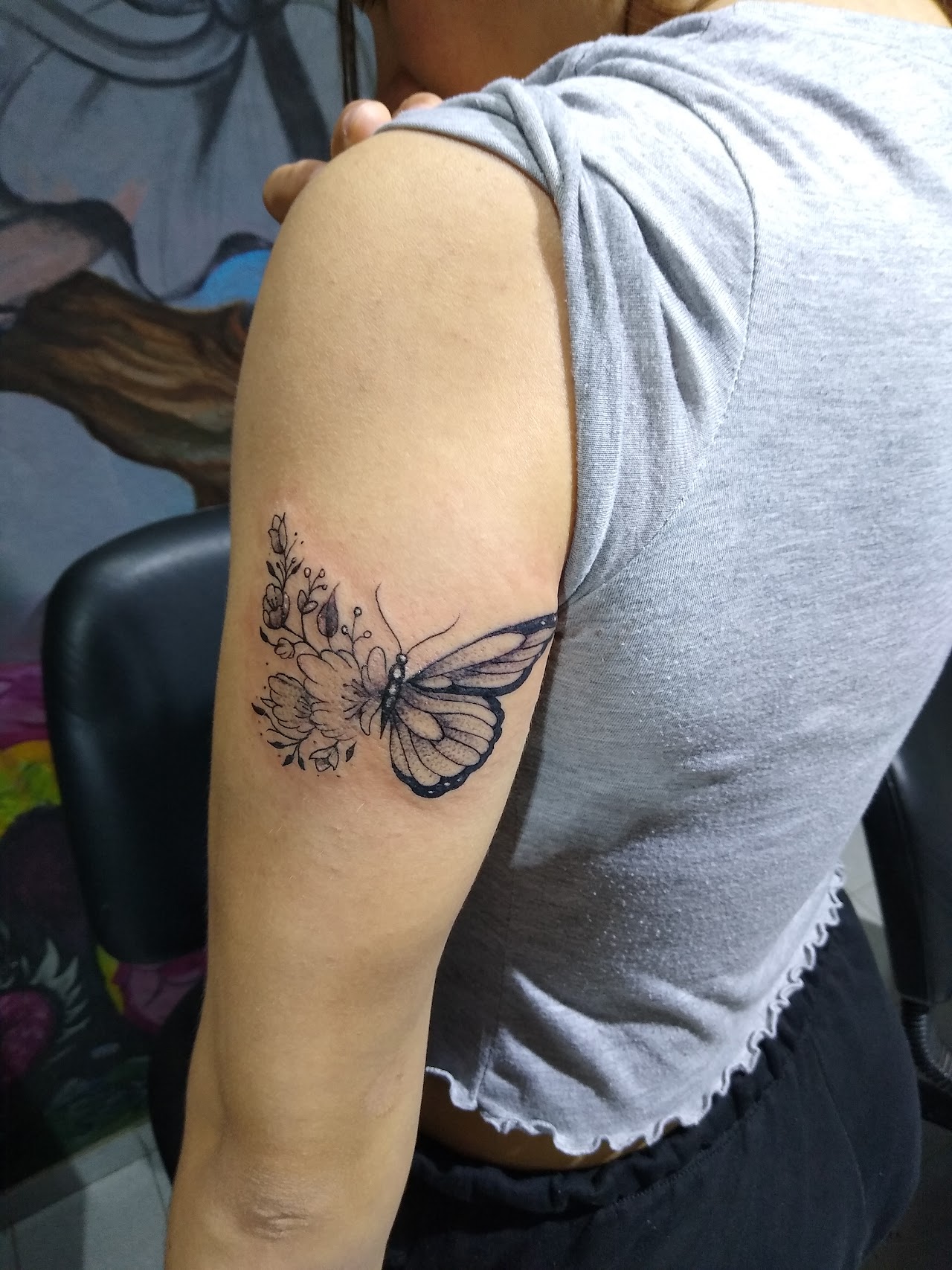 Mariposa y flores en línea fina sobre brazo